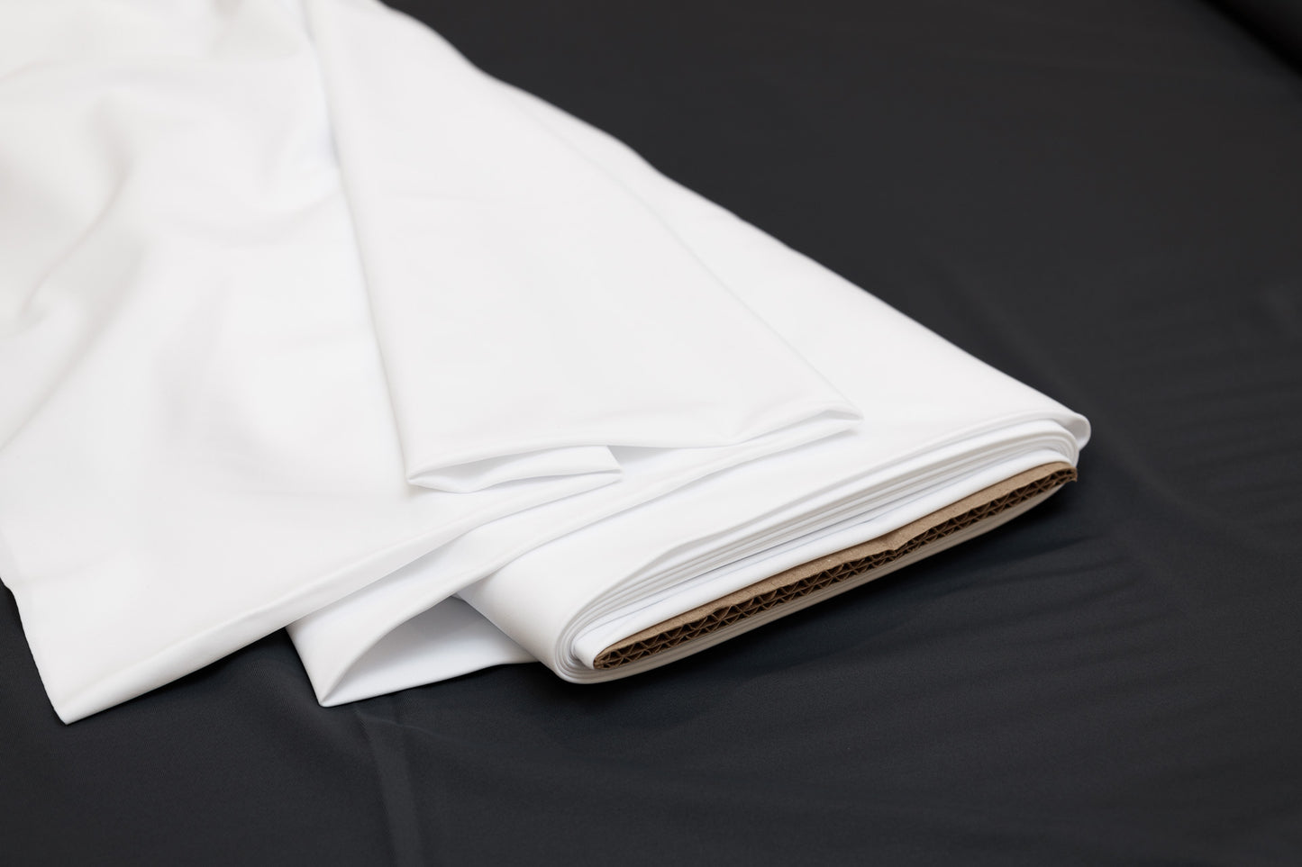 A folded white spandex fabric on a black background, associated with athletic or dancewear.