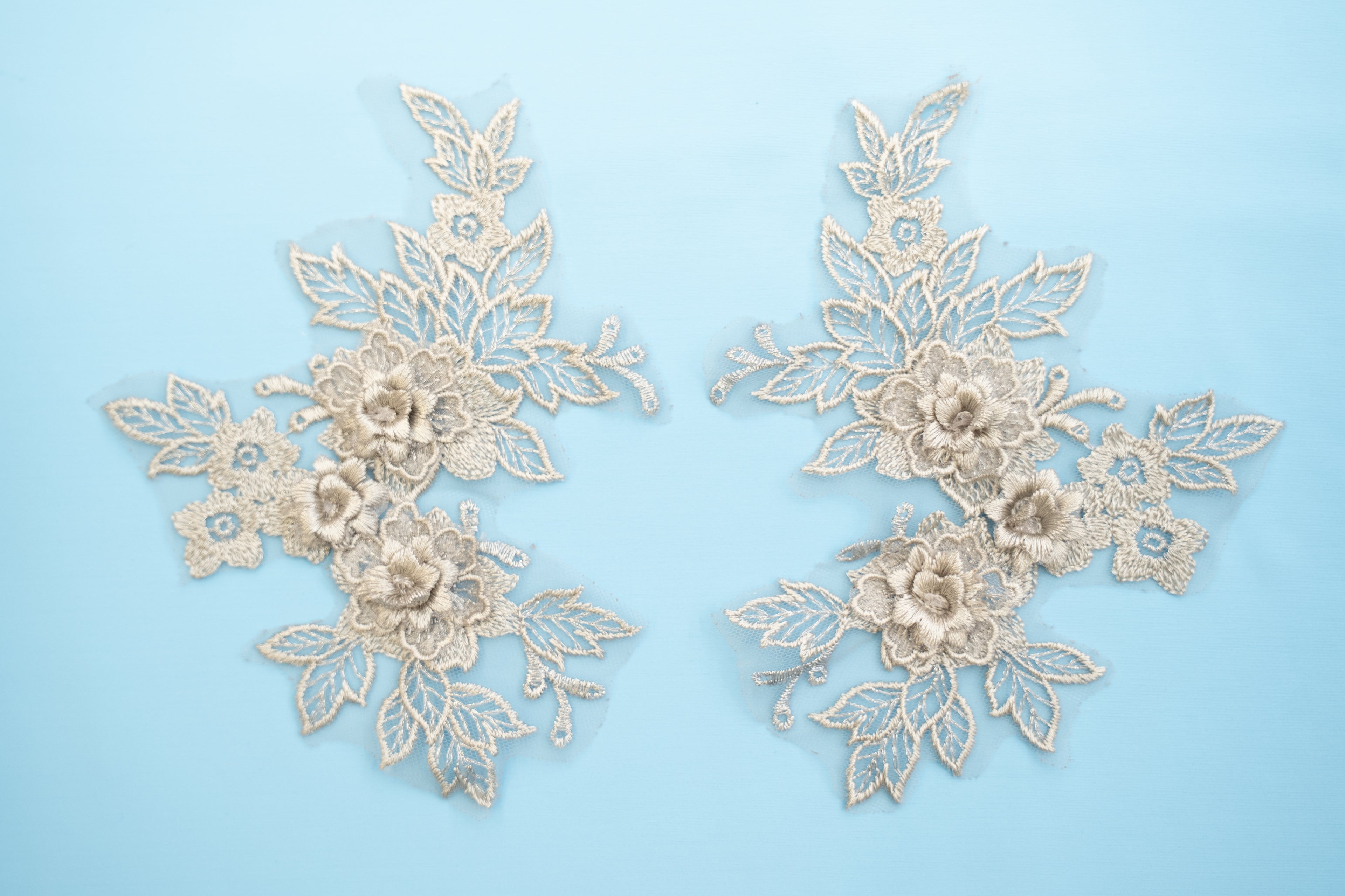 Pair of decorative lace appliqués on a light blue background