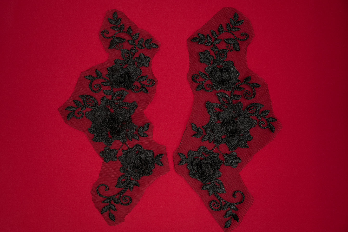 Pair of black lace appliqués on a red background