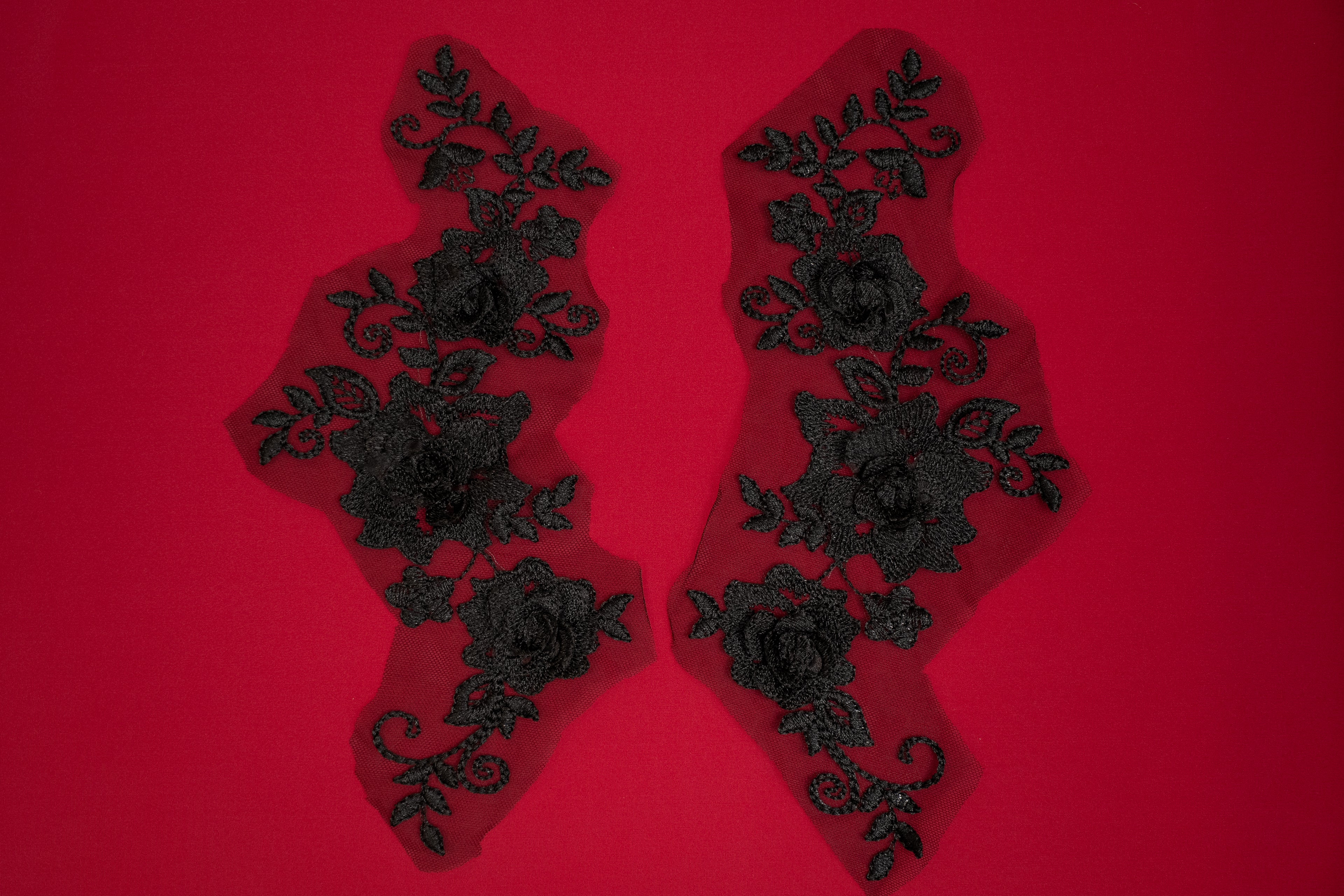 Pair of black lace appliqués on a red background