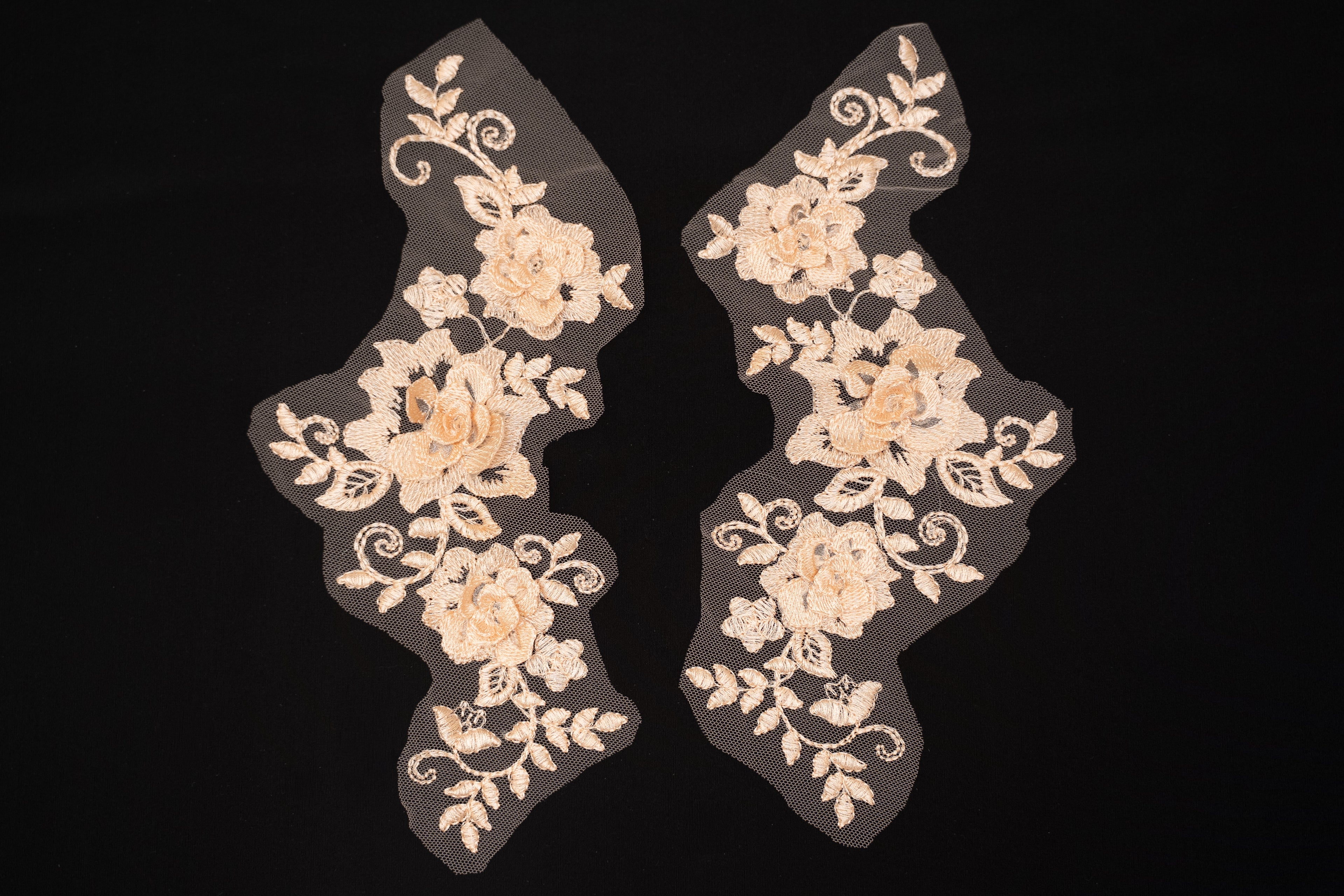 Pair of beige floral lace appliqués on a black background