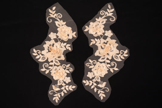 Pair of beige floral lace appliqués on a black background