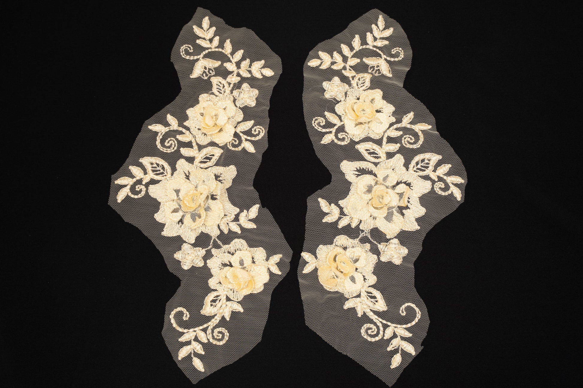 Pair of floral lace appliqués on a black background