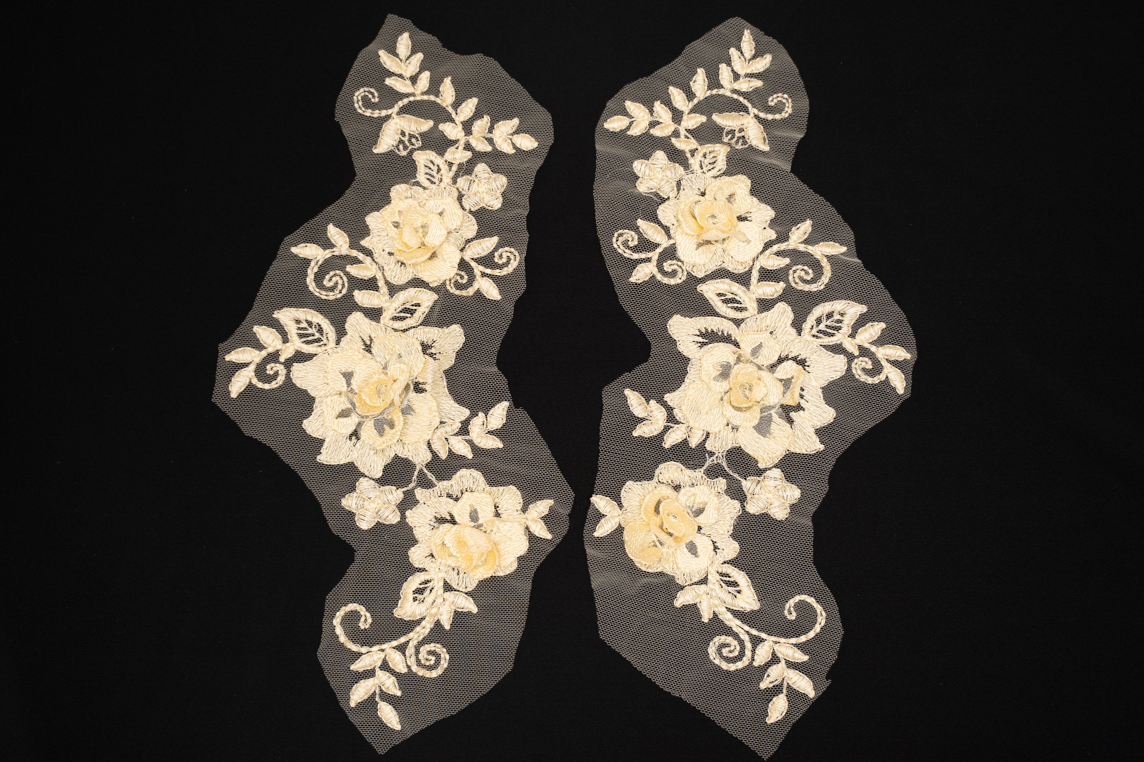 Pair of floral lace appliqués on a black background