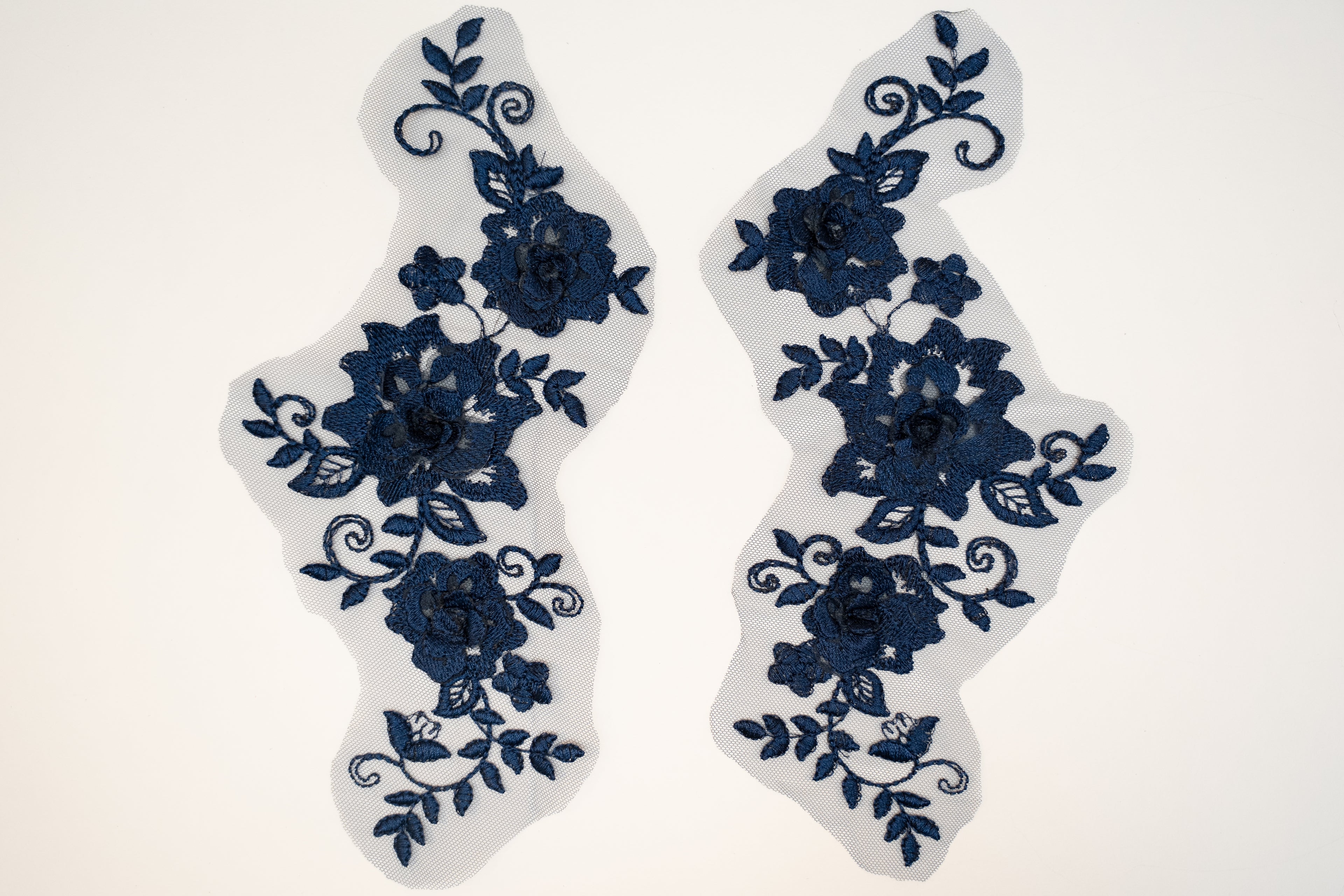 Pair of blue floral lace patches on a white background