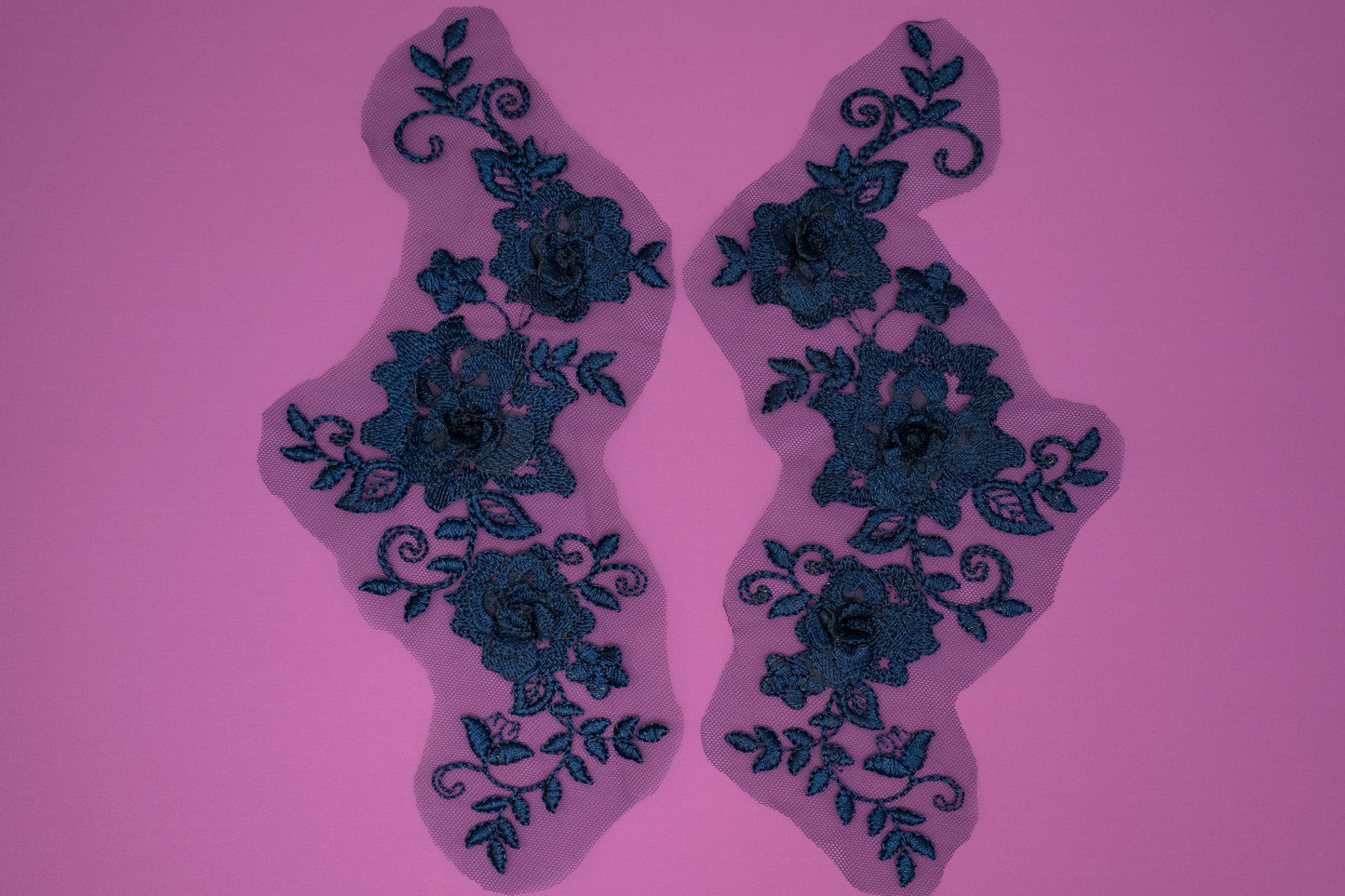 Pair of blue floral lace patches on a pink background