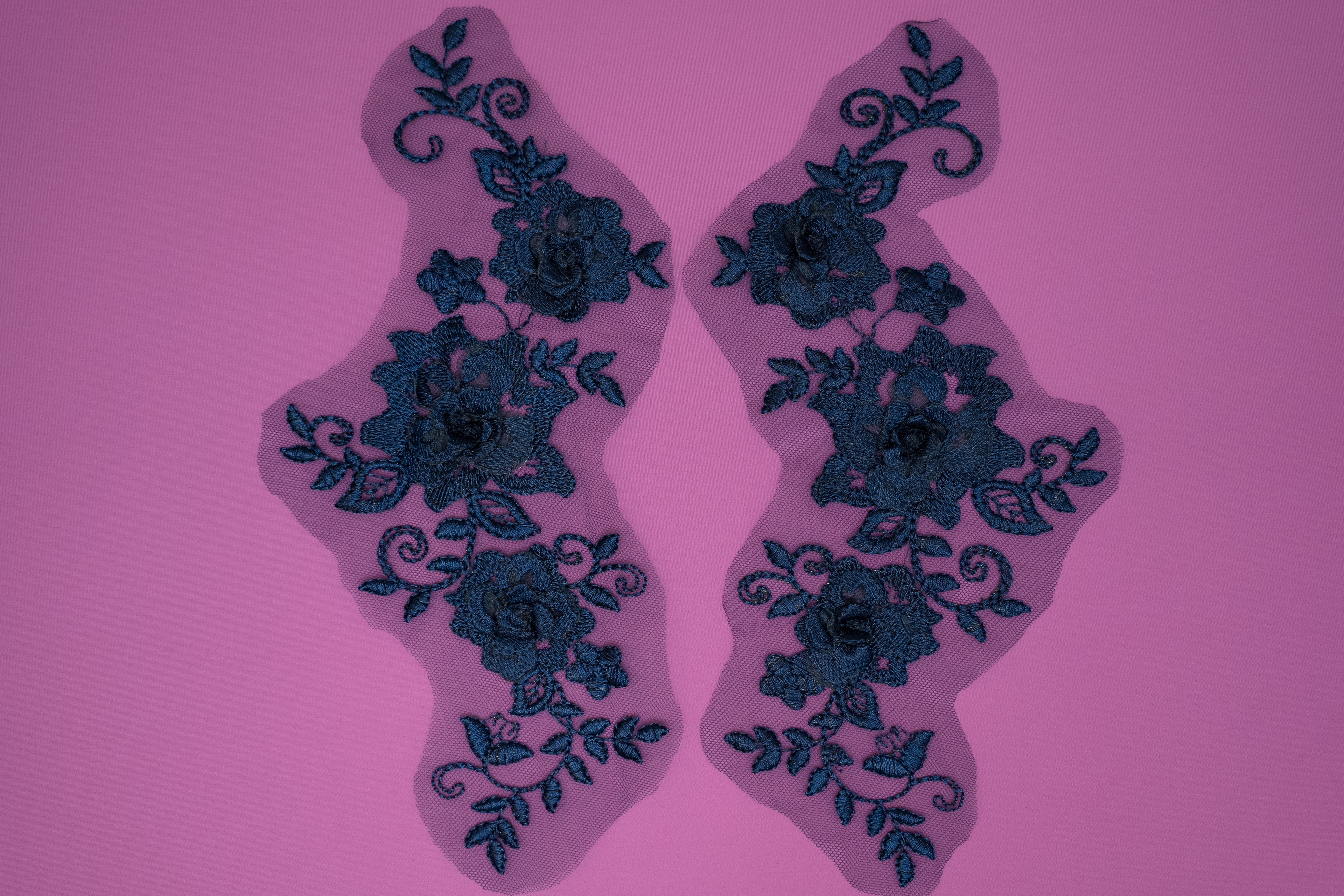 Pair of blue floral lace patches on a pink background