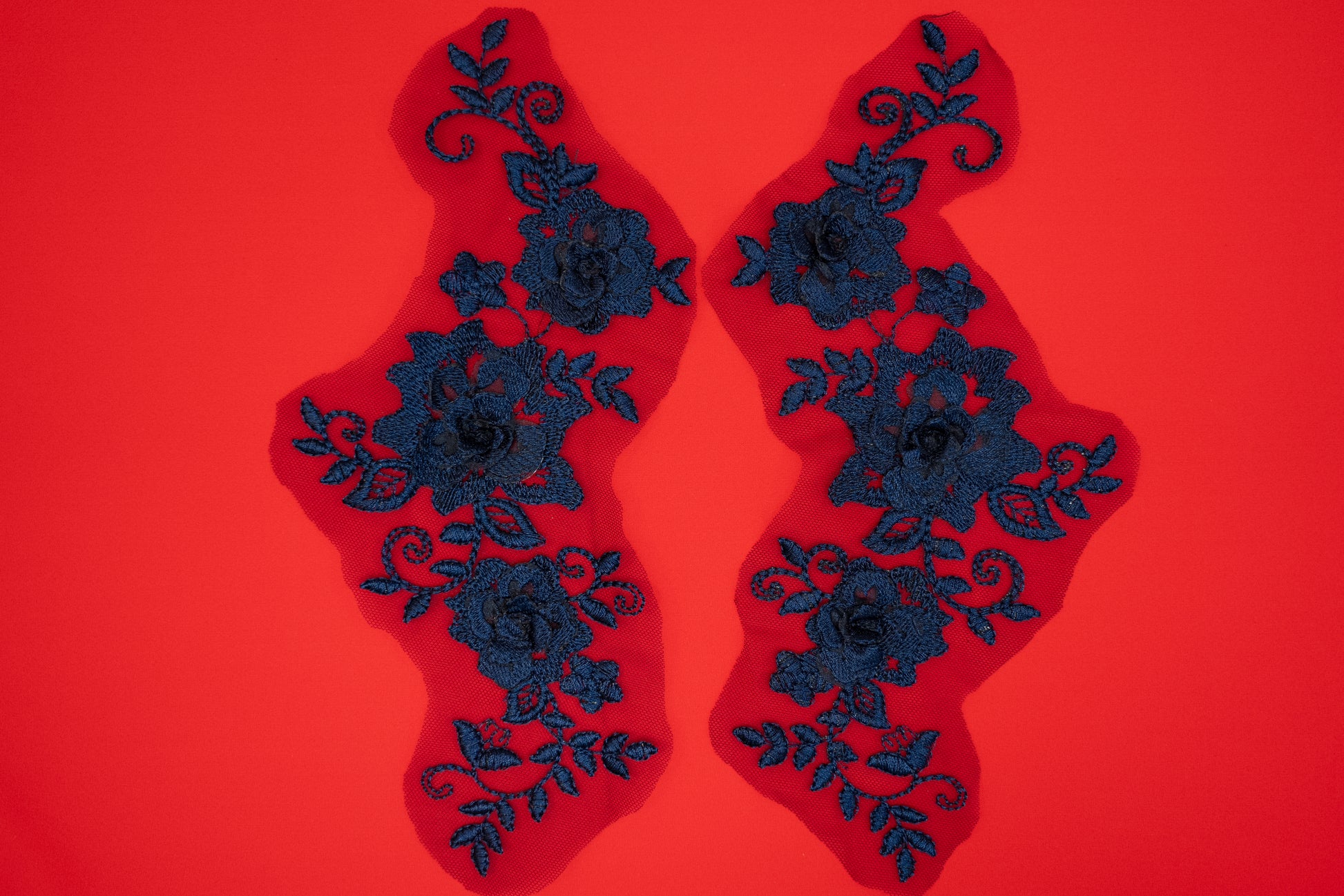 Pair of black floral lace patches on a red background