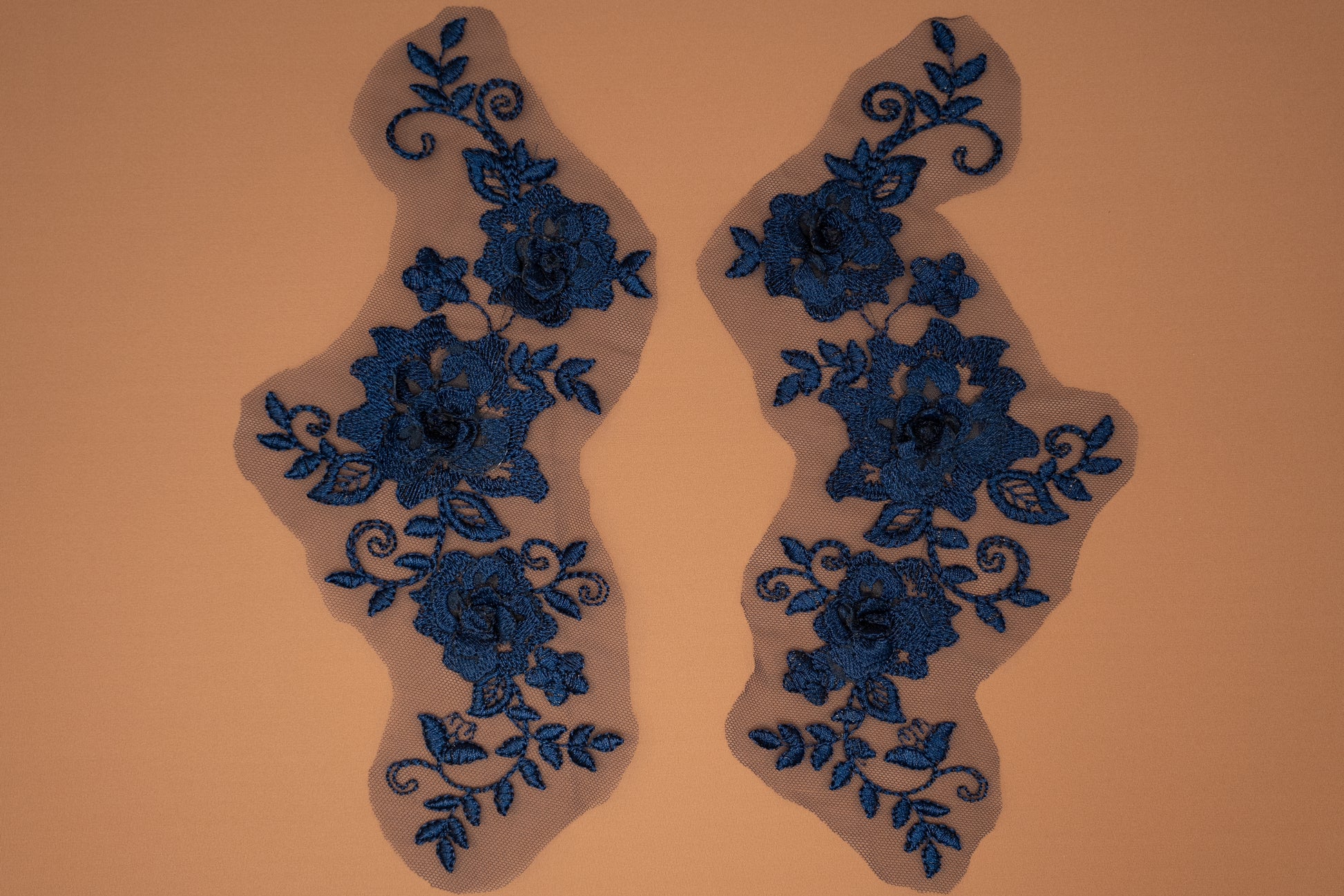 Pair of blue floral lace appliqués on a beige background