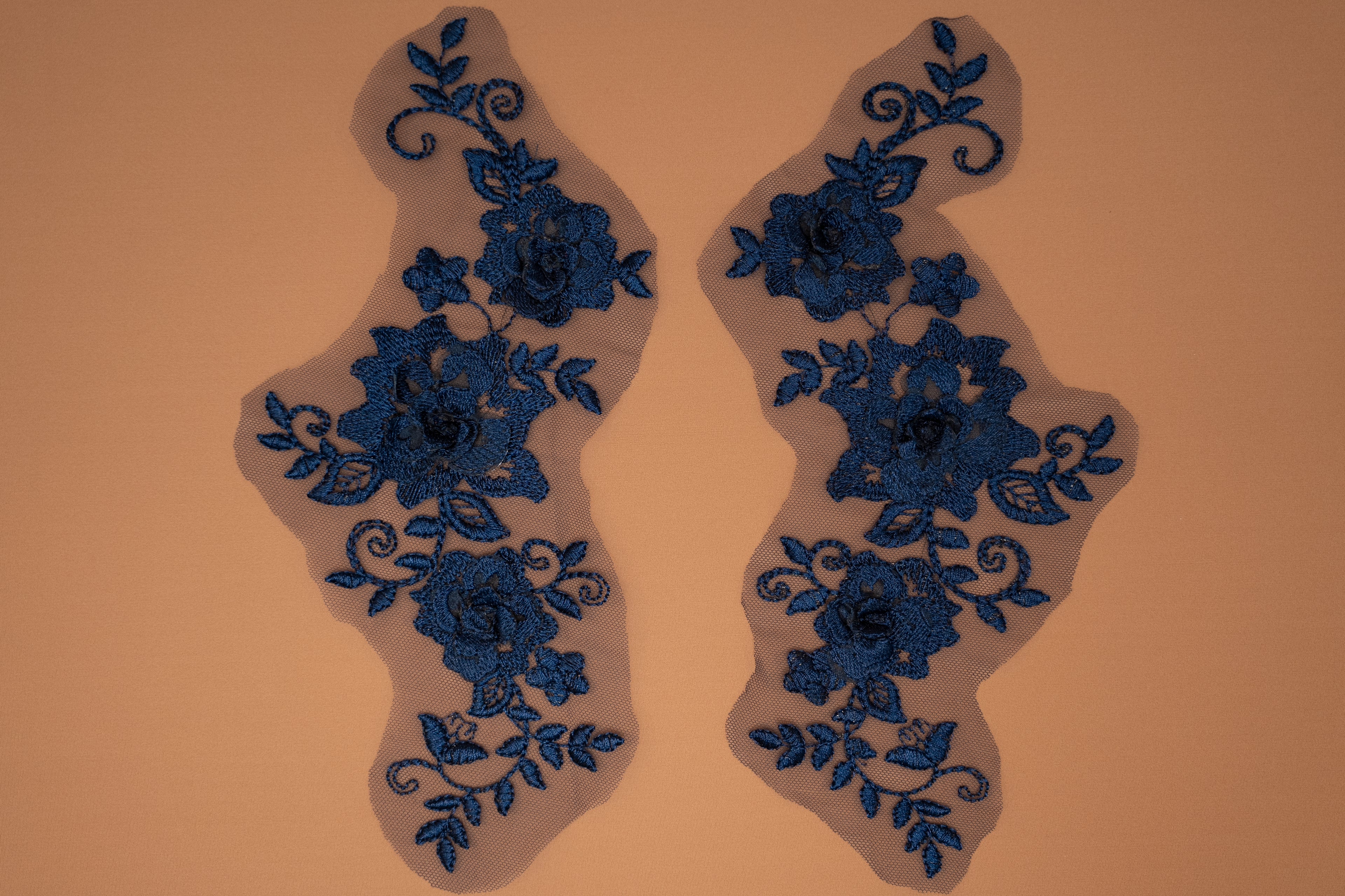 Pair of blue floral lace appliqués on a beige background