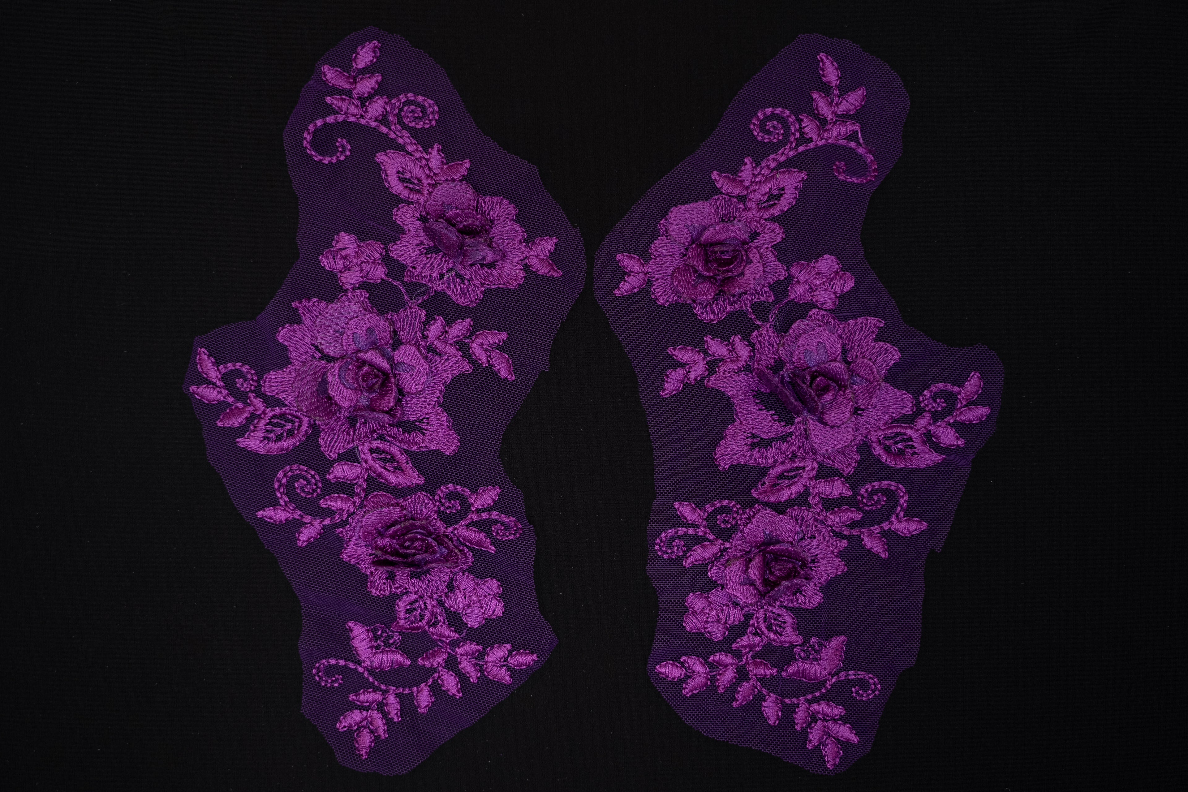 Pair of purple floral lace appliqués on a black background
