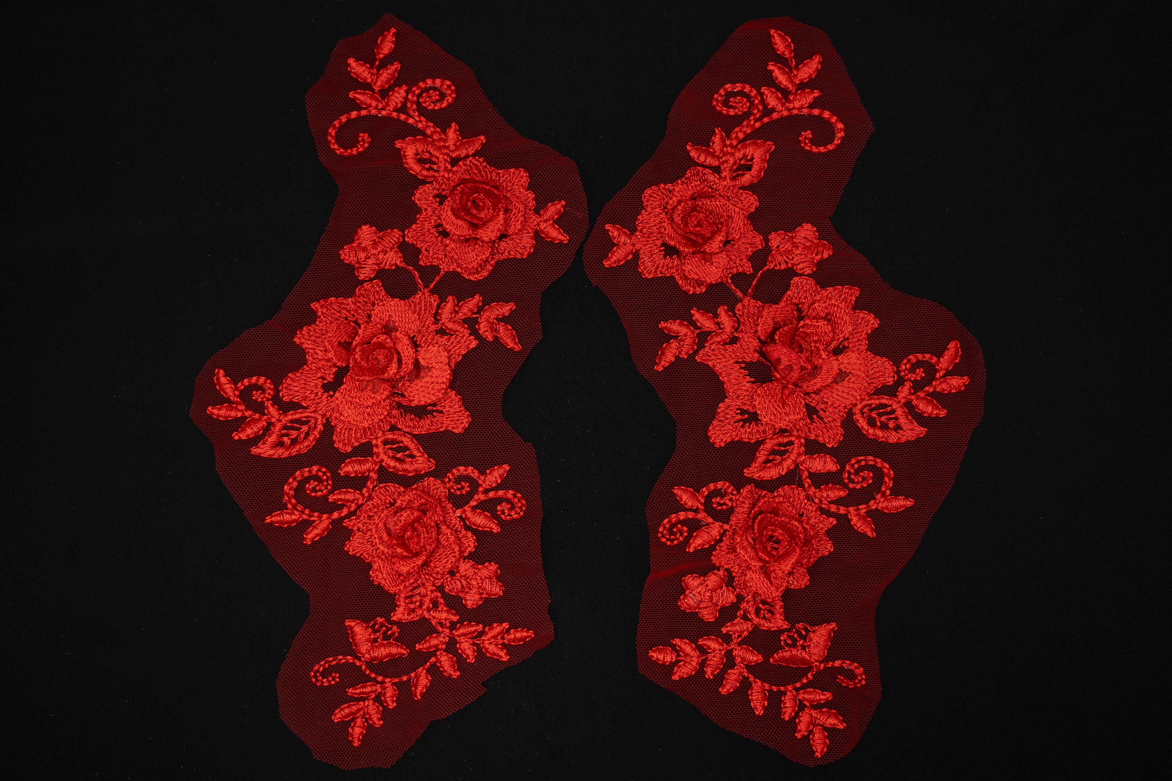 Two red floral lace patches on a black background