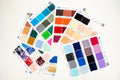 A fan arrangement of multiple fabric and color swatch cards on a plain white background, showing many color options and pattern swatches.