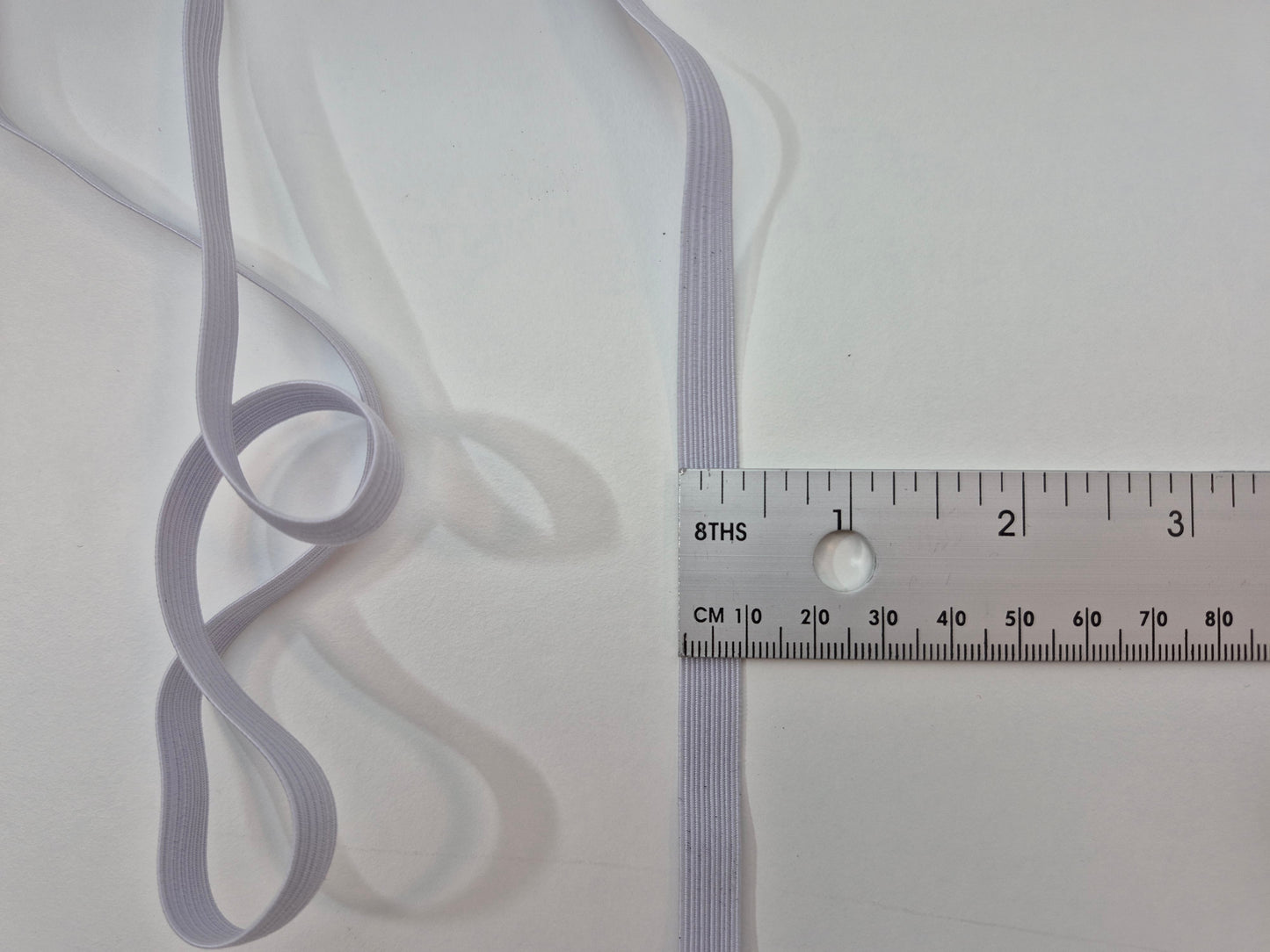 Thin gray ribbon with a ruler for scale on a white background