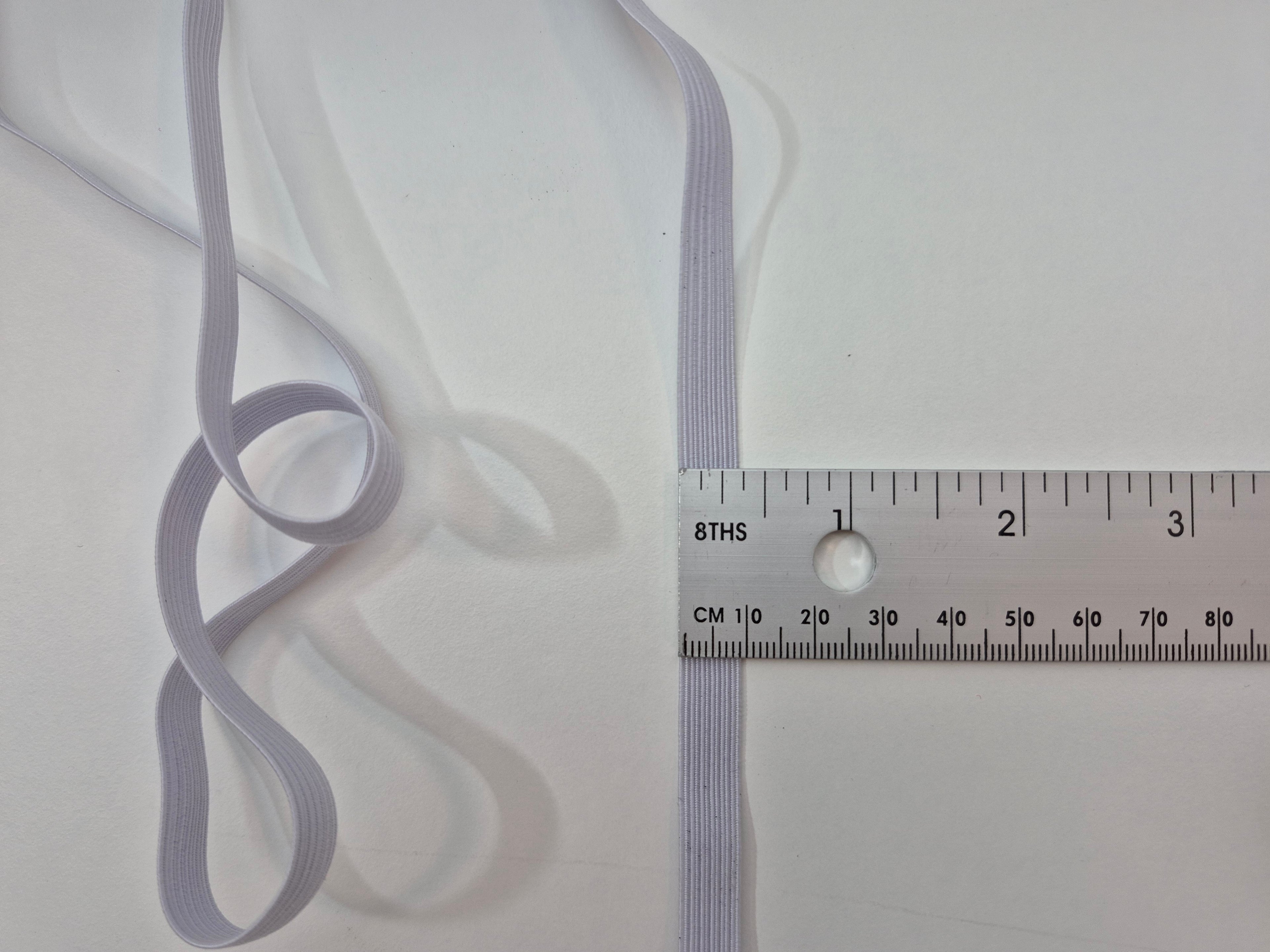 Thin gray ribbon with a ruler for scale on a white background