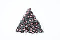A pile of small round sequins arranged in a triangle shape on a plain white background. The sequins have dark gray to black backs with shiny pink and mauve-purple fronts.