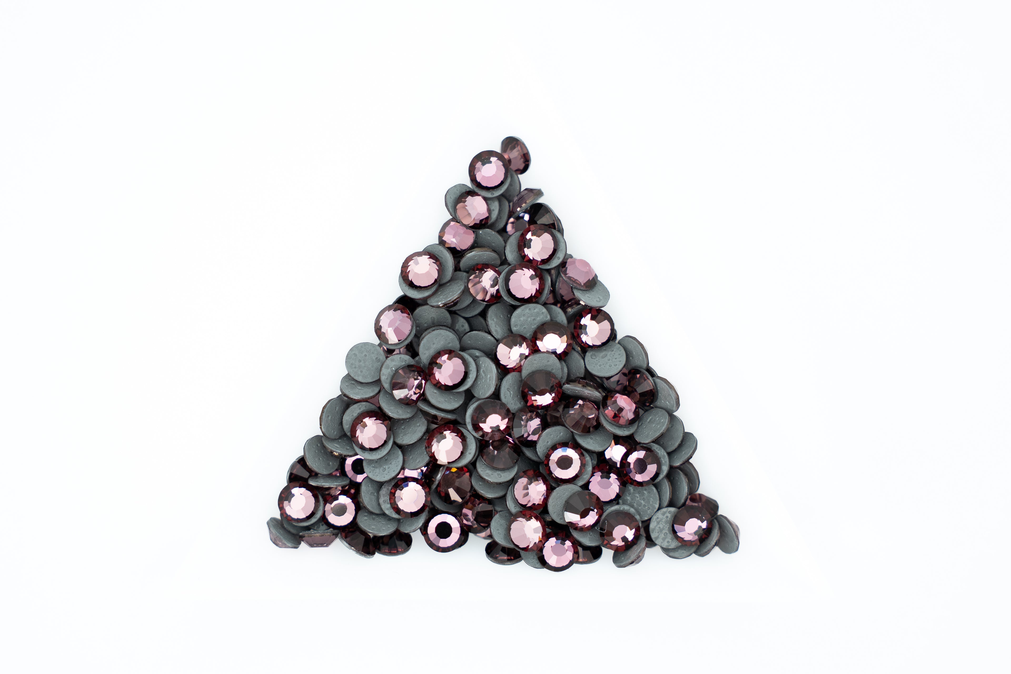 A pile of small round sequins arranged in a triangle shape on a plain white background. The sequins have dark gray to black backs with shiny pink and mauve-purple fronts.