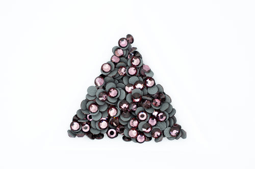 A pile of small round sequins arranged in a triangle shape on a plain white background. The sequins have dark gray to black backs with shiny pink and mauve-purple fronts.